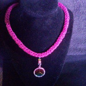 Hand Crafted Hot Pink Tubular beaded necklace with a rainbow color peace sign